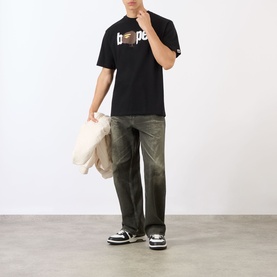 Model wearing BAPE Graffiti Logo Relaxed Fit T-Shirt in black with dark wash wide-leg jeans, carrying a cream tote bag.