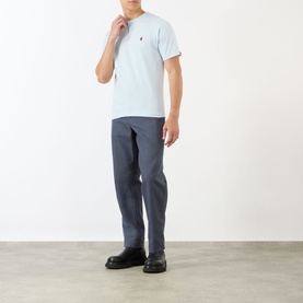 Model wearing BAPE One Point Logo T-Shirt in light blue with chest logo, paired with grey trousers and black leather shoes.