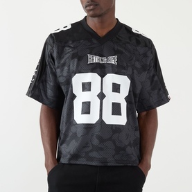 Model wearing BAPE Logo Football Jersey T-Shirt in black with camo pattern, number 88 print, V-neck, and short sleeves