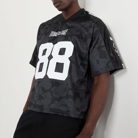 Model wearing BAPE Logo Football Jersey T-Shirt in black with camo pattern, white number 88 print, V-neck, and short sleeves