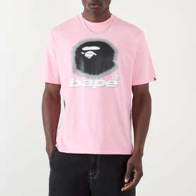 Model wearing BAPE Spray Ape Head Logo T-Shirt in pink with graphic ape print and bape logo, styled with black jeans