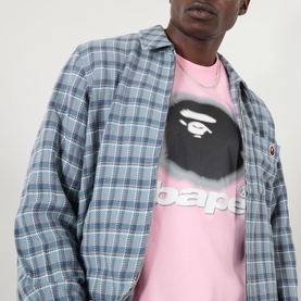 Model wearing BAPE Spray Ape Head Logo T-Shirt in pink with grey plaid overshirt. Ape head graphic and logo print to chest.