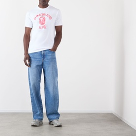 Model wearing BAPE white cotton T-shirt with red ape graphic print, styled with light blue straight-leg jeans and grey trainers