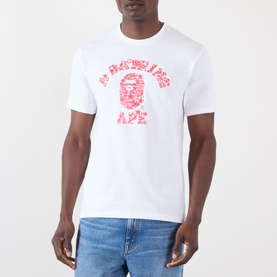 Model wearing BAPE white cotton T-shirt with red camo ape head graphic and collegiate logo print to chest.