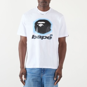 Model wearing BAPE Spray Ape Head Logo T-Shirt in white, featuring spray-effect ape graphic and logo print, styled with blue jeans.