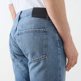 Model wearing Citizens of Humanity Elijah Straight-Leg Trousers in Shadow Blue, rear view showing five-pocket styling and logo patch.
