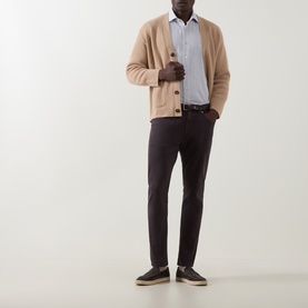 Model wearing Eleventy camel wool-cashmere cardigan, styled with light blue shirt, dark trousers and grey trainers.