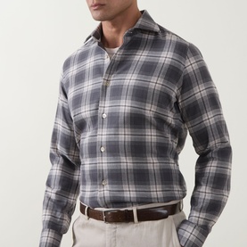 Model wearing Eleventy dark grey large plaid check cotton casual shirt, styled with beige trousers and brown belt.