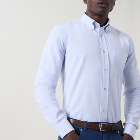 Model wearing Eleventy light blue cotton casual shirt with button-down collar and chest pocket, styled with brown leather belt and navy trousers.