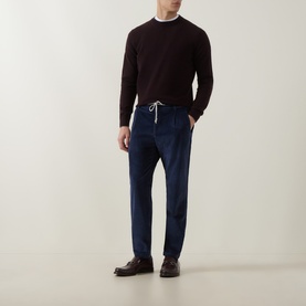Model wearing Eleventy cashmere crew neck in Rosso E Gr Fumo, styled with navy drawstring trousers and dark brown loafers.
