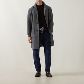 Model wearing Eleventy cashmere crew neck in grey, styled with a grey overcoat, navy trousers and dark leather shoes.