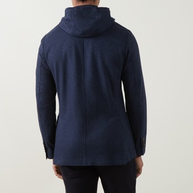Model wearing Eleventy blue hooded jacket, rear view, shown with black trousers. Textured fabric with button cuffs.