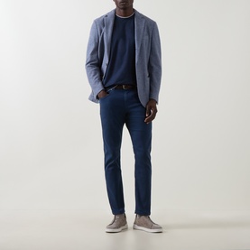 Model wearing Eleventy light blue cotton-wool blazer jacket, styled with navy knitwear, blue trousers and grey slip-on shoes.
