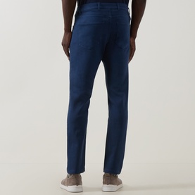Model wearing Eleventy blue slim-fit jeans, rear view, styled with beige suede trainers
