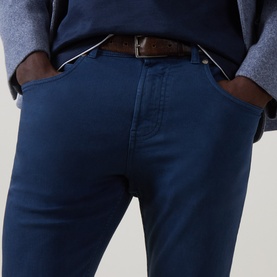 Model wearing Eleventy blue slim-fit jeans in cotton-elastane blend, styled with a brown leather belt and grey knitwear.