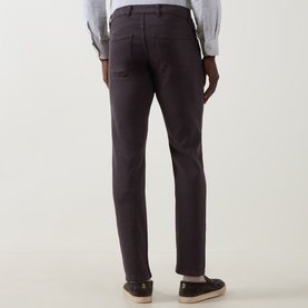 Model wearing Eleventy burgundy slim-fit jeans, rear view, styled with a grey shirt and tan loafers.