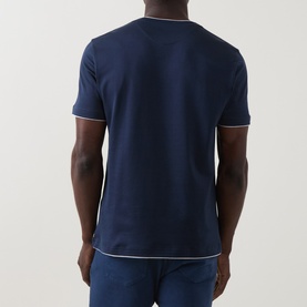 Model wearing Eleventy T-Shirt in blue, rear view, showing white tipped collar and sleeve hems, styled with navy trousers