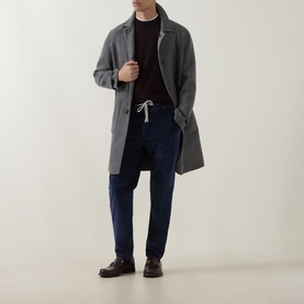 Model wearing Eleventy Drawstring Corduroy Trousers in blue, styled with a grey overcoat, dark knit and brown leather shoes.