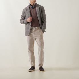 Model wearing Eleventy sand cotton trousers with drawstring waist, styled with grey blazer, brown jumper and dark loafers.