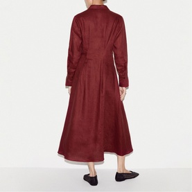 Model wearing a burgundy long-sleeve midi shirt dress with a flared skirt, styled with black flat shoes, rear view.