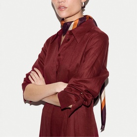 Model wearing burgundy satin shirt dress with pointed collar, styled with a multicolour striped scarf