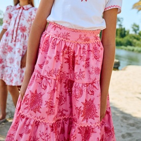 Model wearing Patachou Pink Blossom tiered maxi skirt with floral print, styled with a white embroidered top, outdoors.