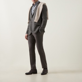Model wearing Slowear mid grey casual shirt, styled with dark charcoal suit, waistcoat, cream scarf draped over shoulders, and dark leather shoes.