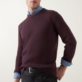 Model wearing Slowear Rib Knit Sweater in burgundy wool with crew neck and ribbed trims, styled over a chambray shirt with black belt.