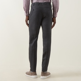 Model wearing Slowear grey wool-cashmere formal trousers, slim cut, rear view. Styled with a pink shirt and beige suede trainers.