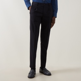 Model wearing slim-fit navy tailored trousers with a front crease, styled with a blue shirt and dark loafers