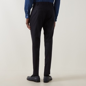 Model wearing dark navy tailored trousers, rear view, styled with a blue shirt and black loafers