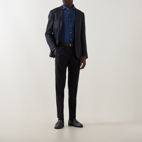 Model wearing navy blazer and trousers with blue shirt, brown belt, and dark leather shoes