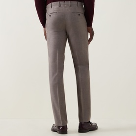 Model wearing Slowear beige formal wool trousers, rear view, styled with dark burgundy top and brown loafers.