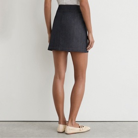 Model wearing Reiss dark blue denim mini skirt, rear view, styled with cream woven loafer flats