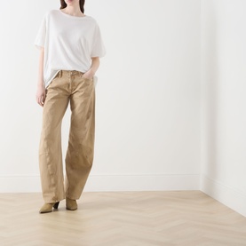 Model wearing Free People Oat Latte wide-leg cotton jeans with a white T-shirt and tan heeled boots.