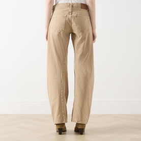 Model wearing Free People Oat Latte jeans, rear view, relaxed wide-leg fit in cotton, styled with brown belt and heeled boots