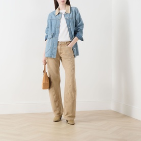 Model wearing Free People Oat Latte wide-leg jeans in cotton, styled with a light blue denim jacket and tan shoulder bag.