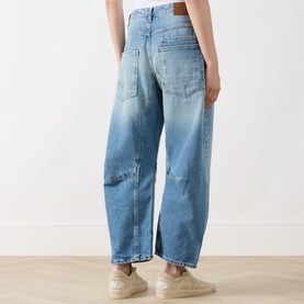 Model wearing Free People Minimalist Moxi Barrel-Leg Jeans in County Fair, mid-wash blue, showing rear patch pockets and contrast stitching