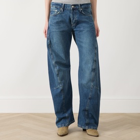 Model wearing Free People blue wide-leg jeans in mid-wash denim with faded detailing, styled with beige shoes