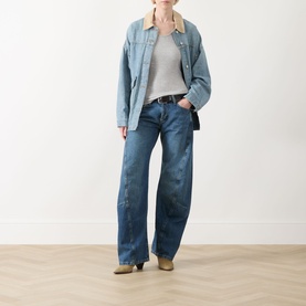 Model wearing Free People blue wide-leg jeans in 100% cotton, styled with a denim jacket, grey top, and tan ankle boots.