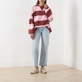 Model wearing Free People V-Insert Striped Sweater in Strawberry Wine Comb, oversized fit with wide stripes, styled with light blue wide-leg jeans