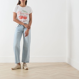Model wearing Free People cherry combo graphic tee with light blue wide-leg jeans and beige lace-up trainers.