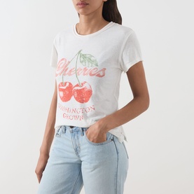 Model wearing Free People Cherry Combo graphic tee with cherry print, styled with light wash blue jeans.