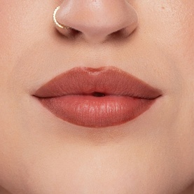 Kash Beauty Lip Lock Lip Stain in Off Record, a muted terracotta-nude shade worn on lips, with gold nose ring visible
