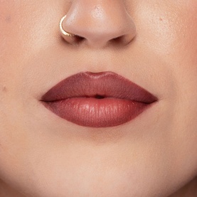 Model with Kash Beauty Lip Lock Lip Stain in Off Record, a muted rose-brown shade, shown applied to lips with gold nose ring visible.