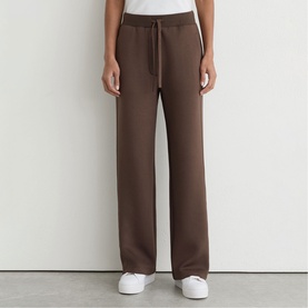 Model wearing Reiss mocha brown wide-leg drawstring trousers, styled with white trainers