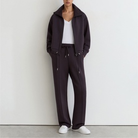 Model wearing Reiss grape burgundy wide-leg trousers with drawstring waist, styled with matching zip-up jacket and white V-neck top.