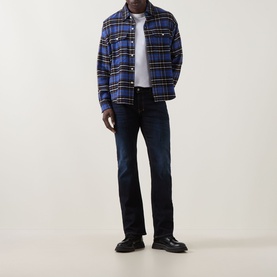 Model wearing Diesel 2007 Zatiny Bootcut Jeans in dark blue with tobacco stitching, styled with blue plaid overshirt and black shoes.