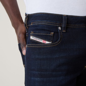 Model wearing Diesel 2007 Zatiny Bootcut Jeans in dark blue with tobacco stitching and logo patch detail on back pocket.