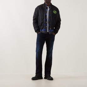 Model wearing Diesel 2007 Zatiny Bootcut Jeans in dark blue, styled with a black bomber jacket and plaid shirt.